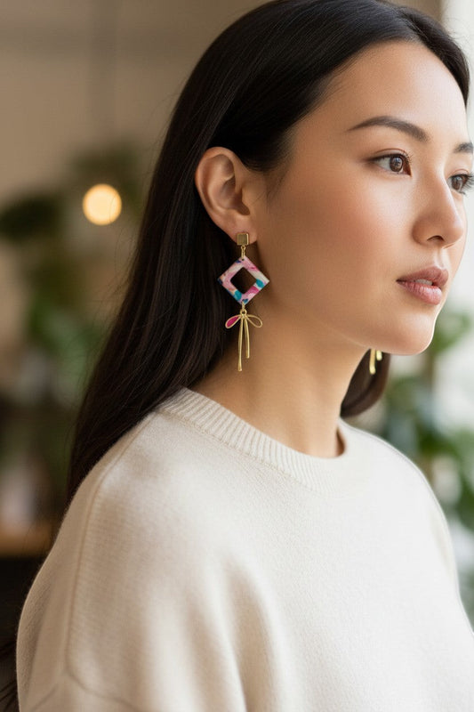Lakelynns Designs abstract diamond dangle earrings with pink, blue, teal, white pattern and gold bow accent.