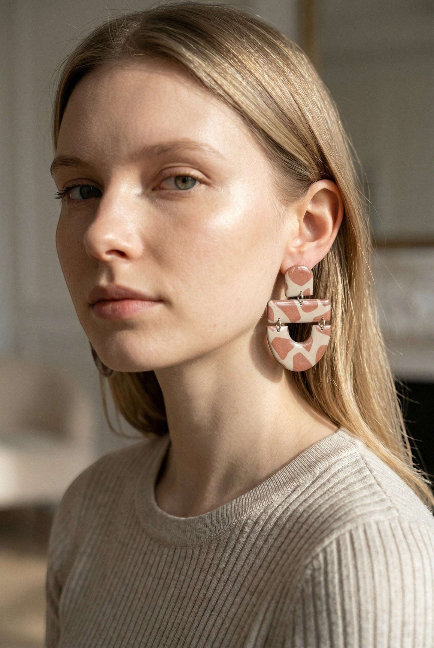 Lakelynns Designs abstract arch dangle earrings in beige with pink spots, made of polymer clay.