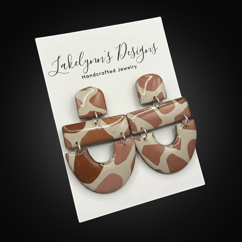 Lakelynns Designs abstract arch dangle earrings in earthy brown and blush polymer clay with a unique pattern.