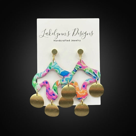 Lakelynns Designs abstract wavy polymer clay dangle earrings with brass discs in pink, blue, green, and orange.