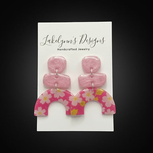 Lakelynns Designs abstract floral arch earrings in pink with white cherry blossoms and yellow accents. Lightweight resin.