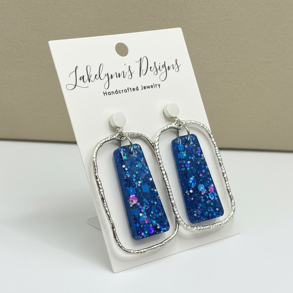 Lakelynns Designs rectangular blue glitter resin dangle earrings with textured silver-tone frames.