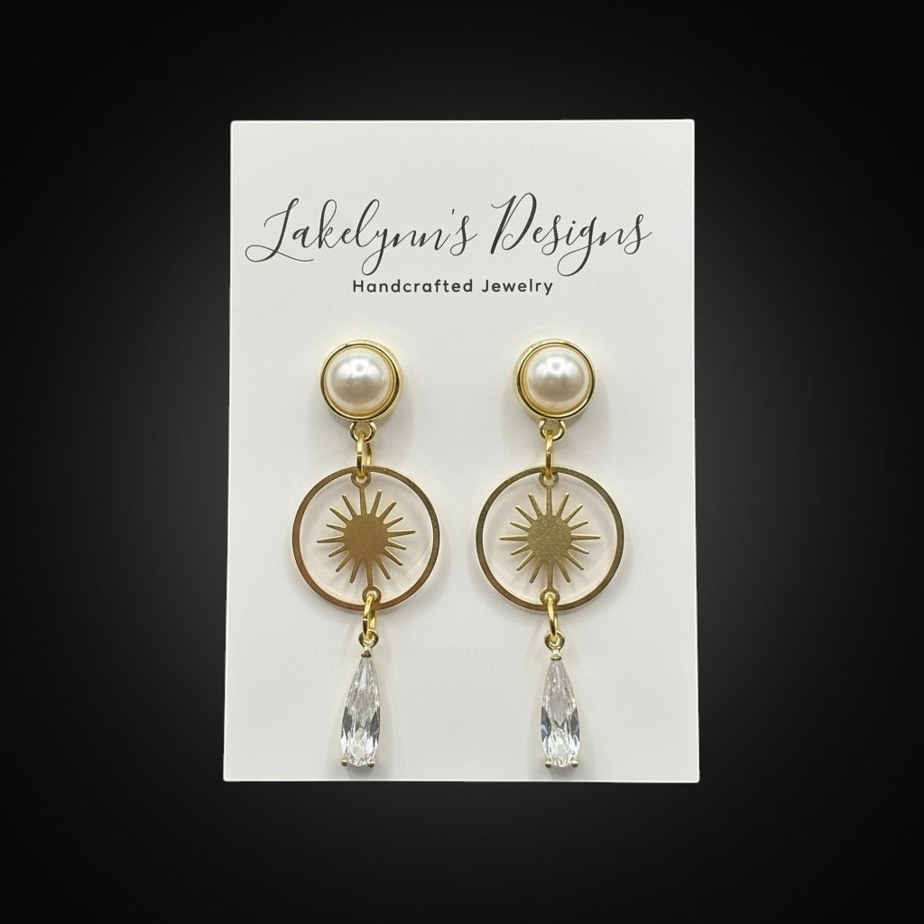 Lakelynns Designs gold-toned celestial drop earrings with pearl top, starburst charm, and crystal teardrop.