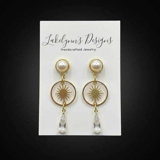 Lakelynns Designs gold-toned celestial drop earrings with pearl top, starburst charm, and crystal teardrop.