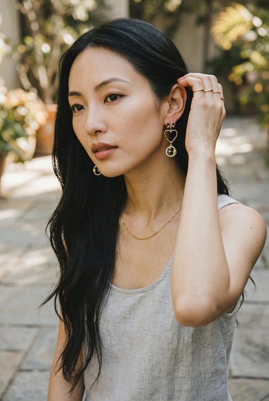 Lakelynns Designs gold-tone celestial heart and moon dangle earrings with bow accent and crystal details.