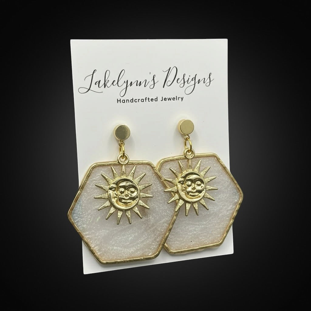 Lakelynns Designs white pearlescent hexagon earrings with gold sun charms and gold hooks.