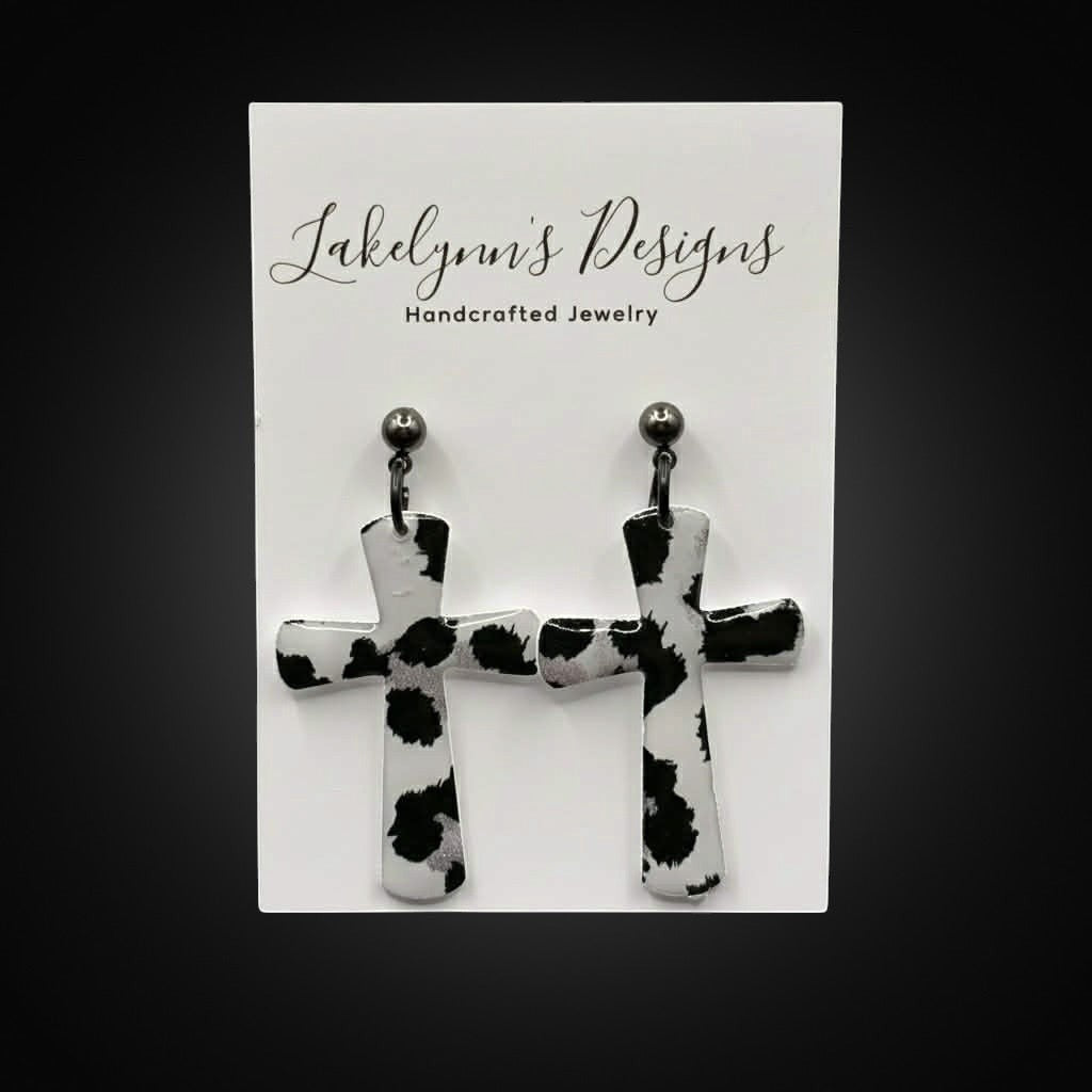 Lakelynns Designs black and white cow print cross earrings with a glossy finish.