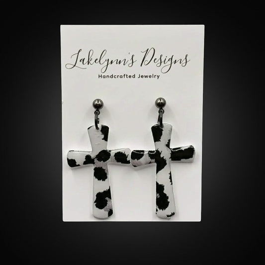 Lakelynns Designs black and white cow print cross earrings with a glossy finish.