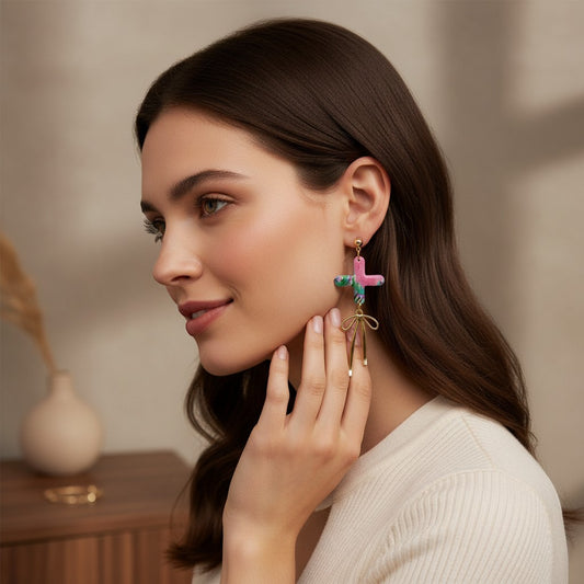 Lakelynns Designs pink, green, and blue cross dangle earrings with gold bow charm.