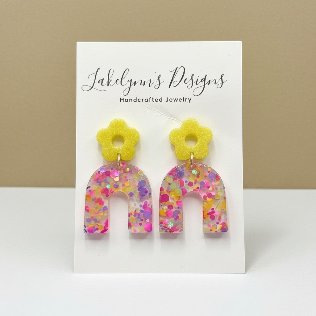 Lakelynns Designs yellow flower arch earrings with pink, purple, and yellow glitter confetti. Lightweight resin.