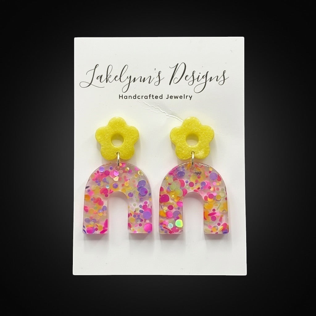 Lakelynns Designs yellow flower arch dangle earrings with pink, purple, and yellow glitter confetti.