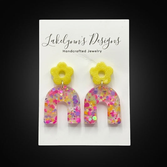 Lakelynns Designs yellow flower arch dangle earrings with pink, purple, and yellow glitter confetti.