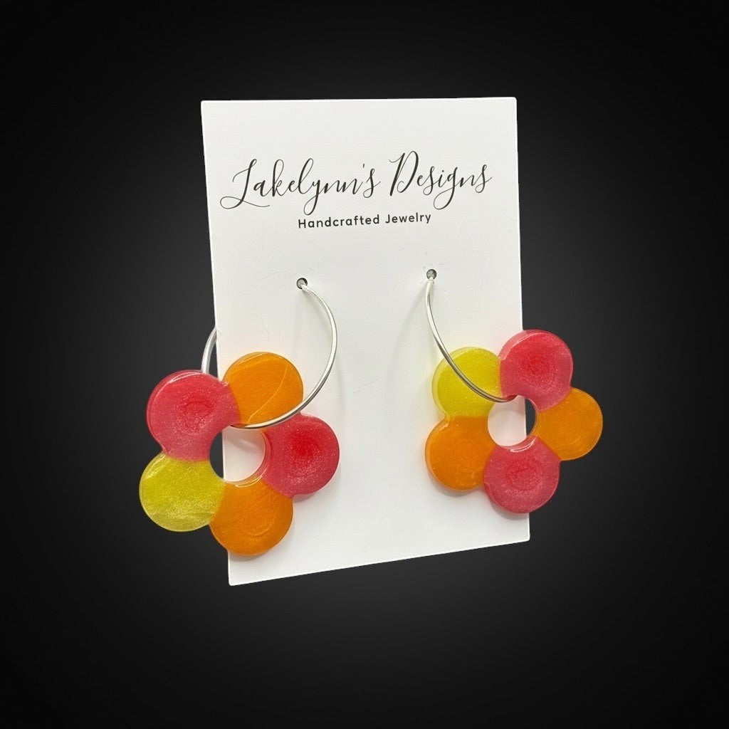 Lakelynns Designs colorful flower hoop earrings in red, orange, and yellow translucent resin with silver-tone hoops.