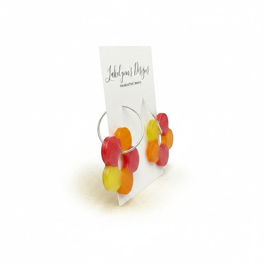 Lakelynns Designs colorful flower hoop earrings in red, orange, and yellow translucent resin with silver-tone hoops.