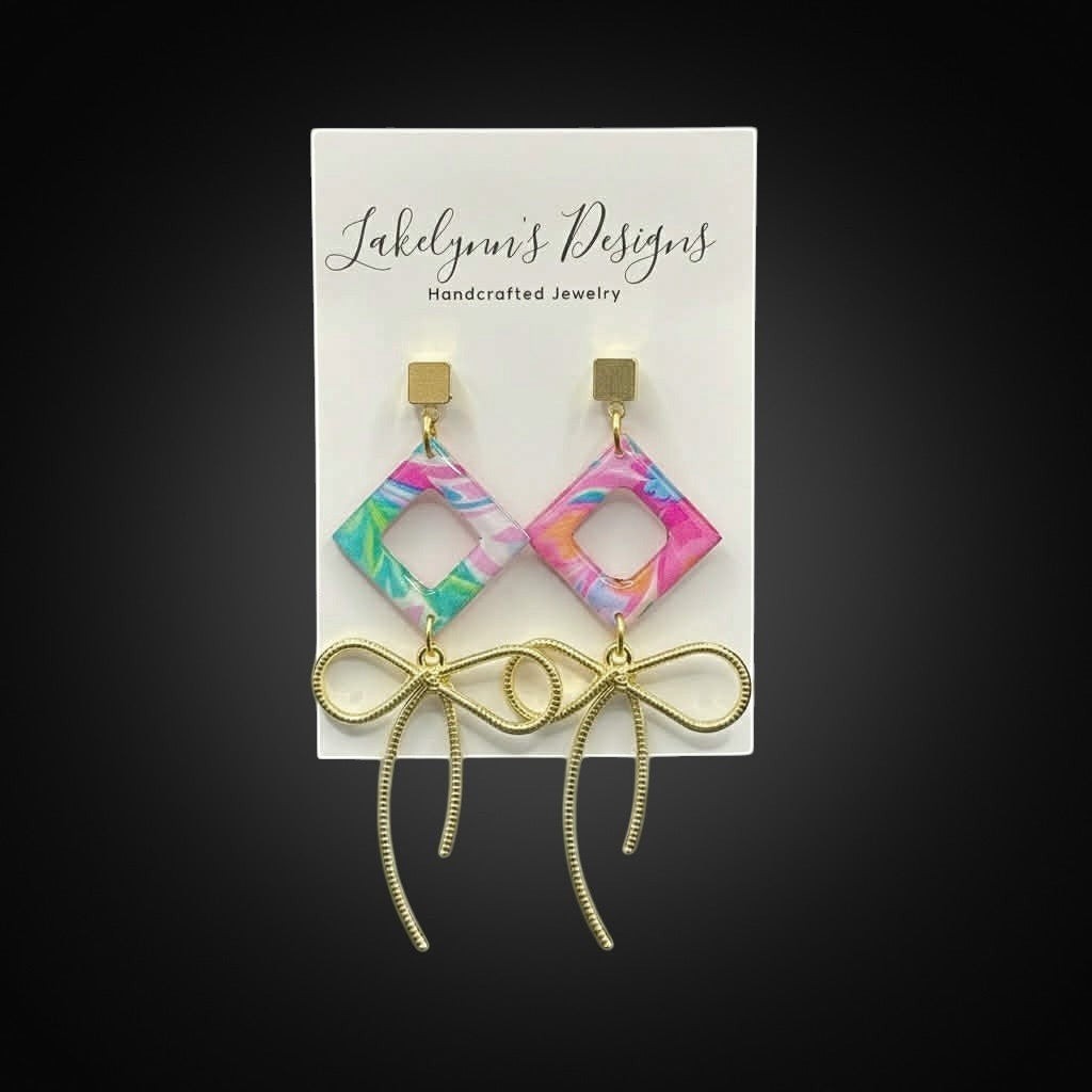 Lakelynns Designs handcrafted polymer clay geometric diamond earrings with gold bow dangles in pink, blue, green, and white.