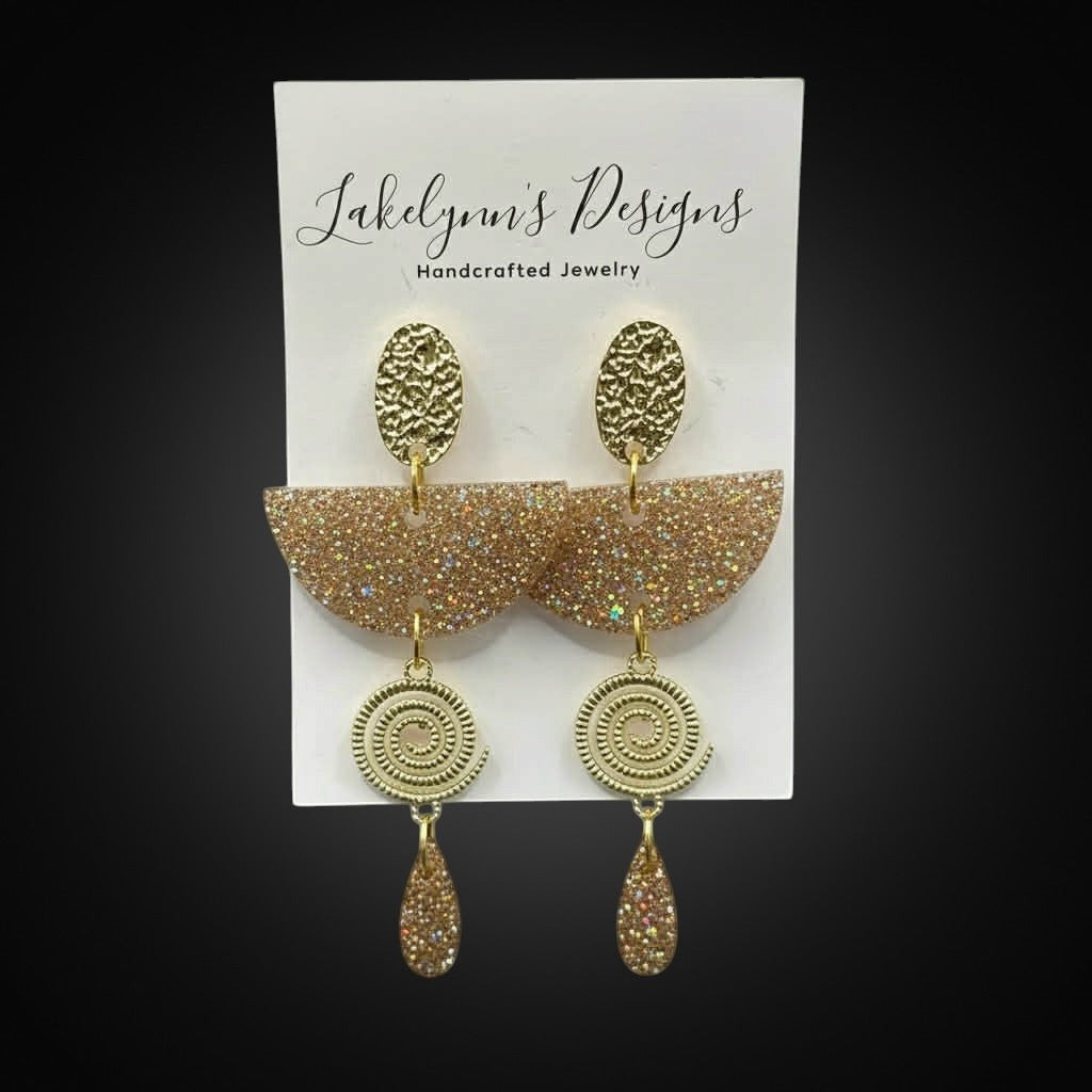 Lakelynns Designs champagne gold glitter acrylic semi-circle earrings with gold-tone spiral and teardrop charms.