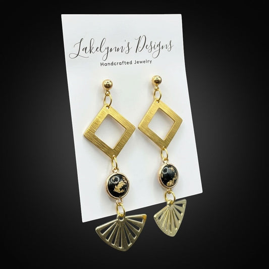 Lakelynns Designs gold-tone geometric fan dangle earrings with black cabochon and gold flecks.