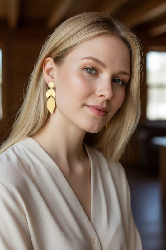 Lakelynns Designs geometric leaf dangle earrings in brushed brass-toned metal. Abstract design with circle, crescent, and leaf shapes.