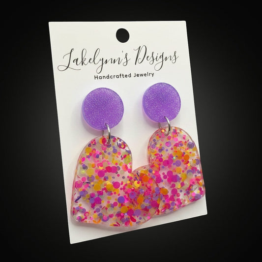 Lakelynns Designs multi-colored glitter heart dangle earrings with purple stud backs. Clear acrylic with pink, yellow, and orange glitter.
