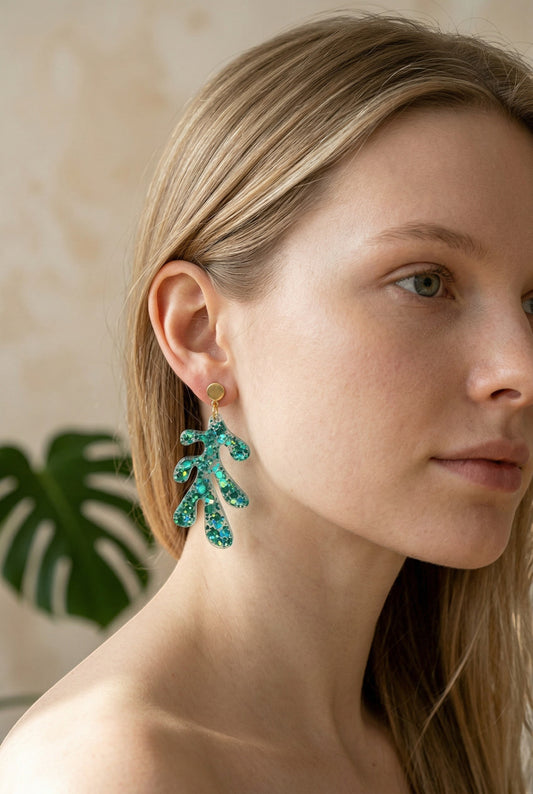 Lakelynns Designs Liliana Glittery Leaf Dangle Earrings in teal resin with green and blue glitter. Gold-tone posts.
