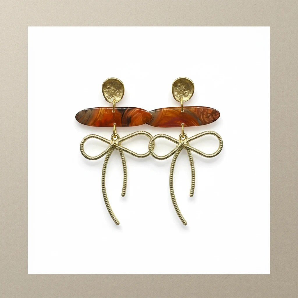 Lakelynns Designs gold bow dangle earrings with marbled orange acrylic beads and textured gold studs.