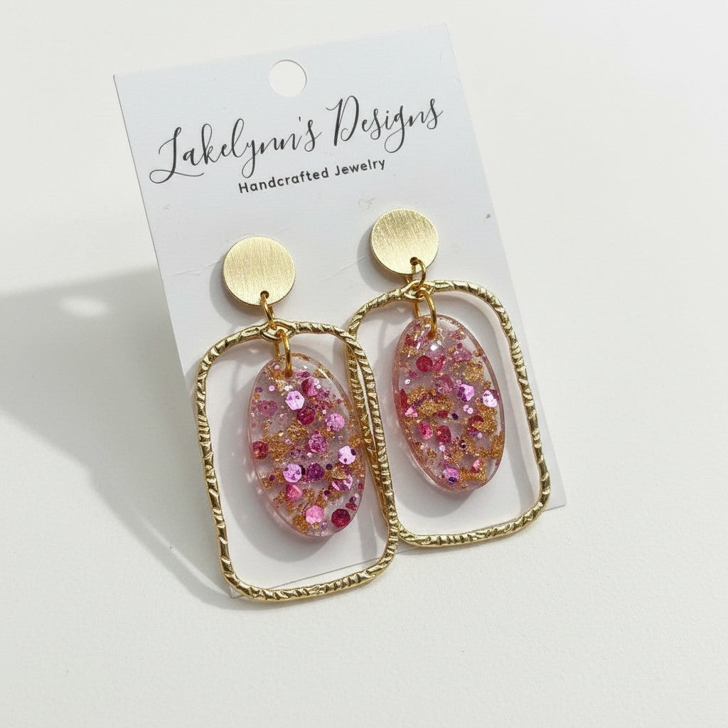 Lakelynns Designs gold geometric earrings with pink and gold glitter oval resin inserts. Modern, lightweight, and dazzling.