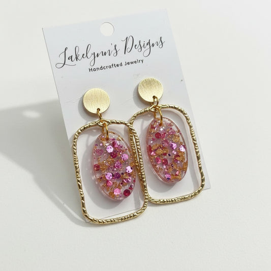 Lakelynns Designs gold geometric earrings with pink and gold glitter oval resin inserts. Modern, lightweight, and dazzling.