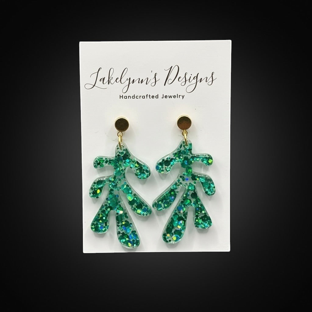Lakelynns Designs green glittery leaf dangle earrings with gold-tone posts. Translucent resin with embedded green and blue glitter.