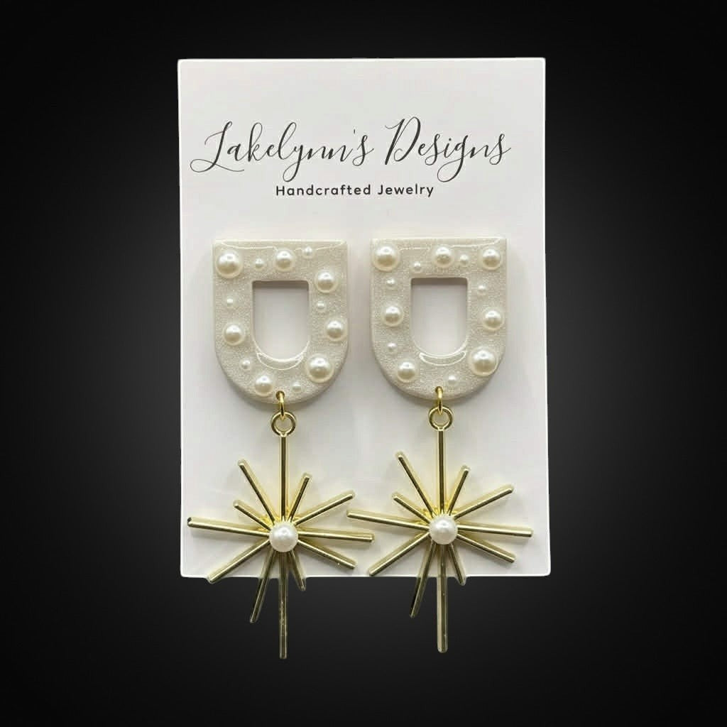 Lakelynns Designs Kendall Starburst Arch Earrings with white pearl-adorned arches and gold starburst charms.
