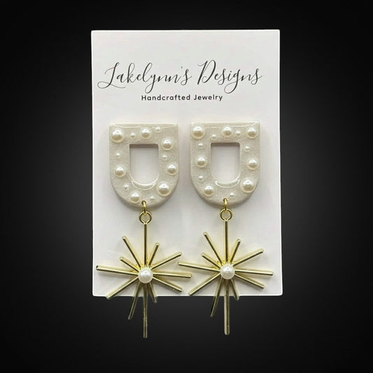Lakelynns Designs Kendall Starburst Arch Earrings with white pearl-adorned arches and gold starburst charms.