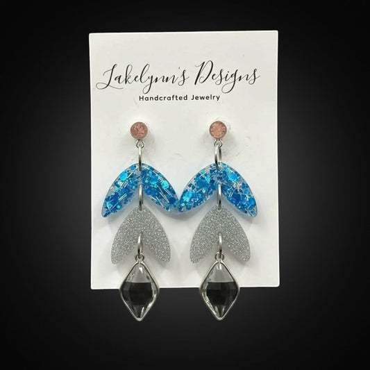 Lakelynns Designs layered leaf dangle earrings with blue glitter resin, silver glitter acrylic, and charcoal grey charms.