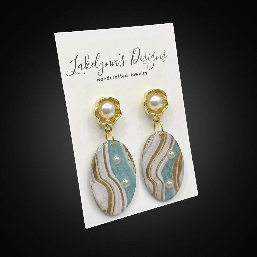 Lakelynns Designs oval dangle earrings with pearl accents, featuring marbled aqua, cream, and gold patterns.