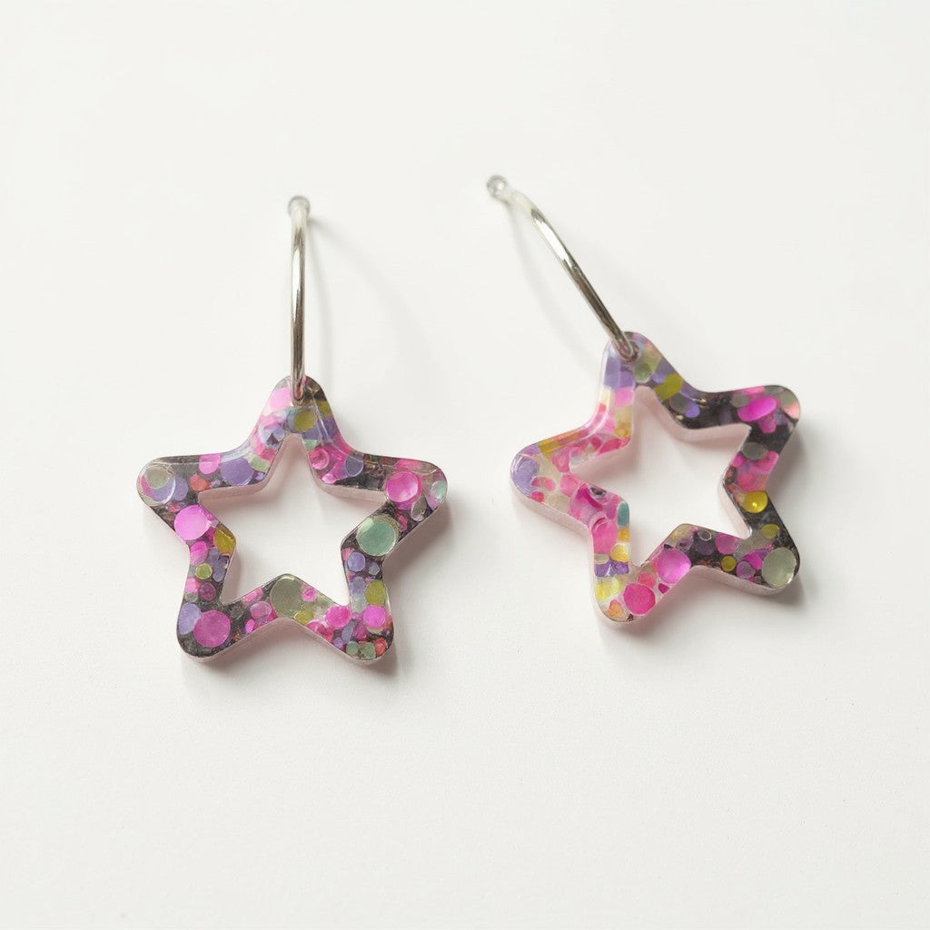 Lakelynns Designs star shaped hoop earrings with multi-colored glitter in clear resin. Silver-toned hook closure.