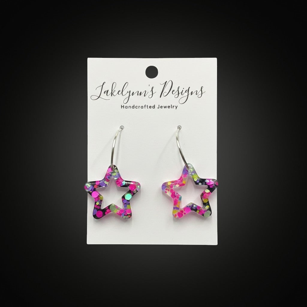 Lakelynns Designs star shaped hoop earrings with multi-colored glitter in clear resin. Silver-toned hook closure.