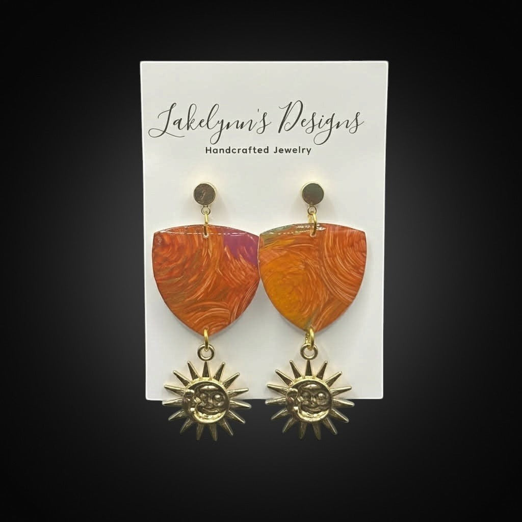 Lakelynns Designs orange and purple polymer clay shield earrings with gold smiling sun charms.