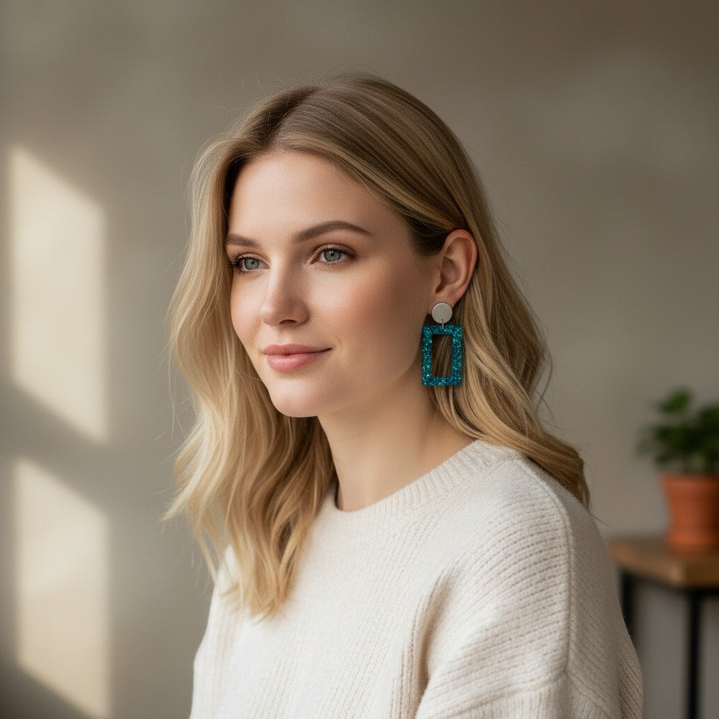 Lakelynns Designs rectangular teal glitter drop earrings with brushed silver studs, worn by a blonde woman.