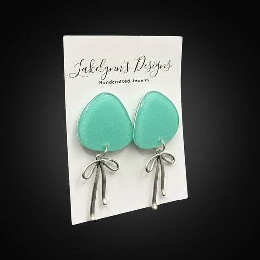 Lakelynns Designs translucent teal teardrop earrings with silver bow charms. Handcrafted jewelry.