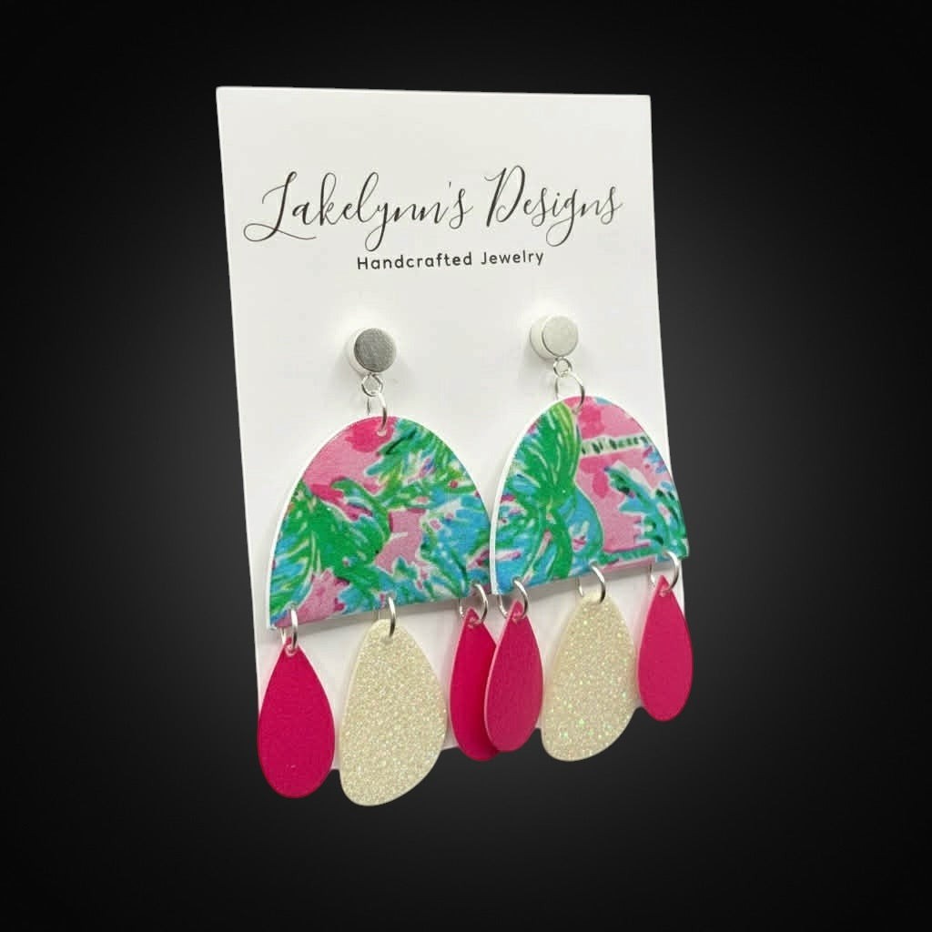 Lakelynns Designs Sky Tropical Arch Dangle Earrings with pink hibiscus, green palm leaves, and glittery white teardrops.