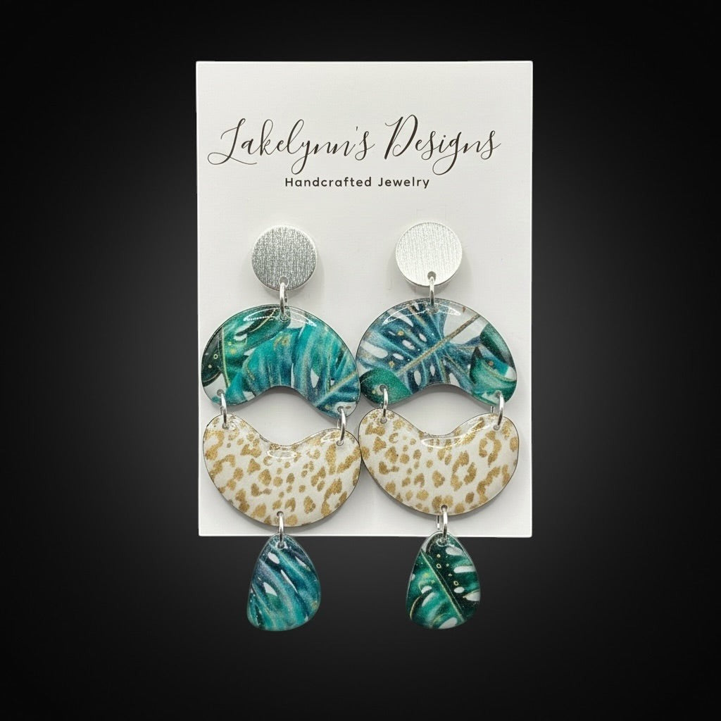 Lakelynns Designs tropical leaf and leopard print dangle earrings with green, blue, gold, and cream colors.