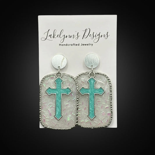 Lakelynns Designs turquoise cross earrings with glitter resin and silver rope edge detail.
