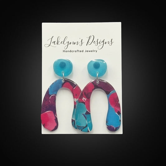 Lakelynns Designs vibrant abstract arch dangle earrings in pink, blue, and purple with glossy finish.
